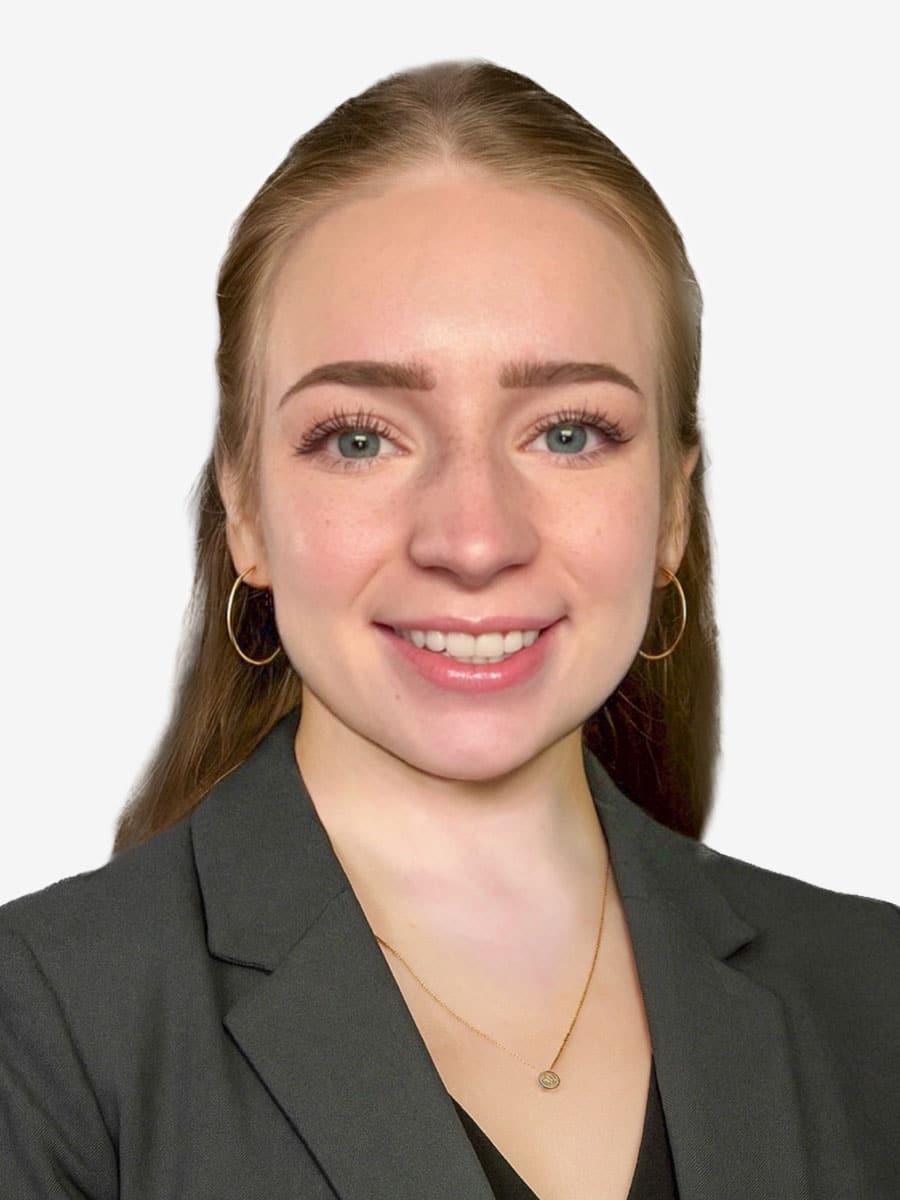 A young woman with long light brown hair, wearing a dark blazer, gold hoop earrings, and a gold necklace, smiles at the camera against a plain white background—introducing McKenzie Sobczak, MS, of the LLP team.